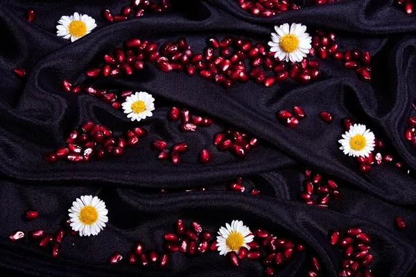 Körner Granatapfelblüten auf schwarzer Seide — Stockfoto