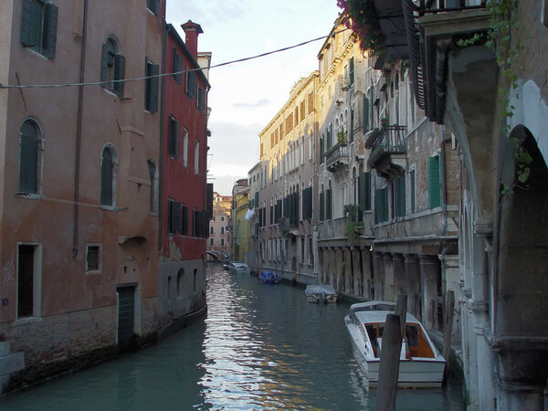Old colorful houses and Motorboats on a canal in Venice. Deep afternoon shadows.