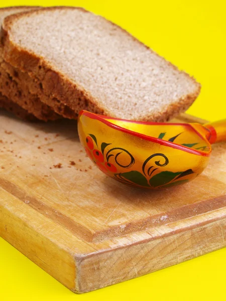Bread, spoon and board on a back — Stock Photo, Image