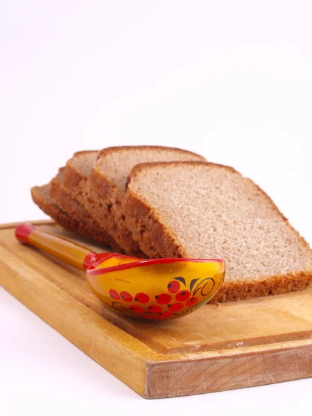 Хлеб, ложка и доска на белом — стоковое фото