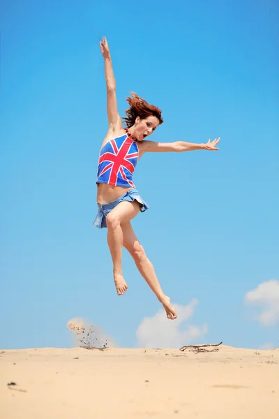 Flickan hoppar på en bakgrund av blå himmel — Stockfoto