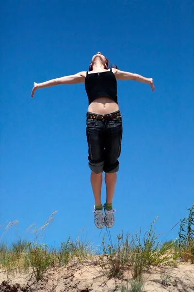 Girl jumping on a background of blue sky — Stock Photo, Image