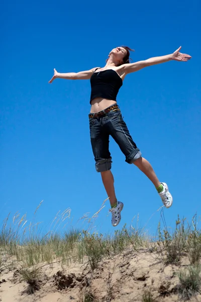 Mädchen springt vor blauem Himmel — Stockfoto