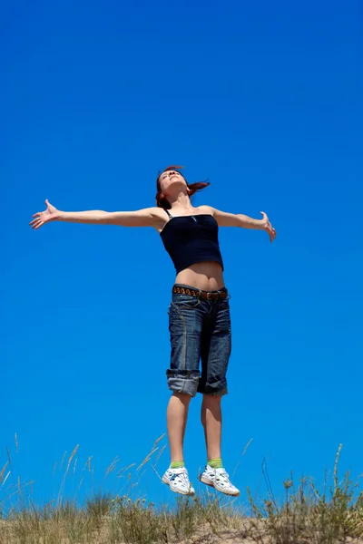ผู้หญิงกระโดดบนพื้นหลังของท้องฟ้าสีฟ้า — ภาพถ่ายสต็อก