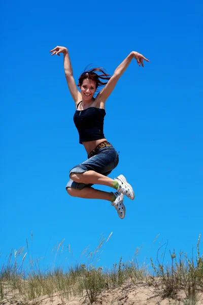 Kız mavi gökyüzü arka plan üzerinde atlama — Stok fotoğraf