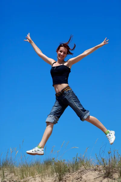 Mädchen springt vor blauem Himmel — Stockfoto