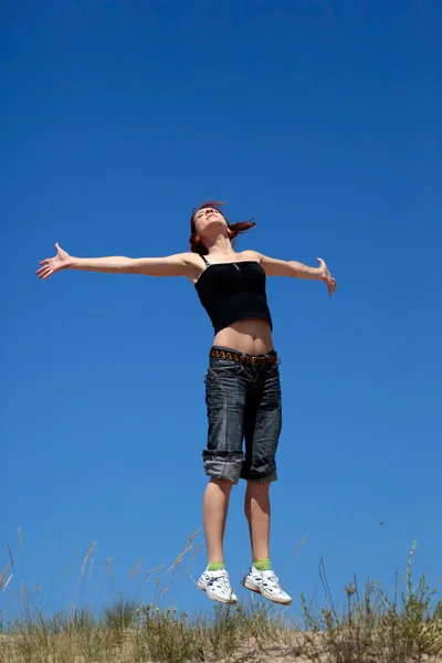 ผู้หญิงกระโดดบนพื้นหลังของท้องฟ้าสีฟ้า — ภาพถ่ายสต็อก