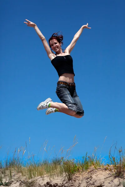 跳跃的蓝蓝的天空背景上的女孩 — 图库照片