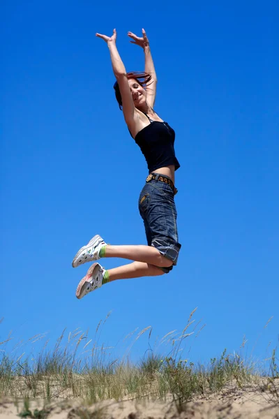 跳跃的蓝蓝的天空背景上的女孩 — 图库照片