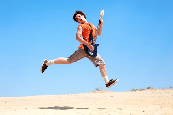 Молодой человек с гитарой прыгает — стоковое фото