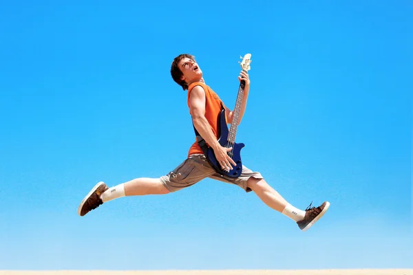 Молодой человек с гитарой прыгает — стоковое фото
