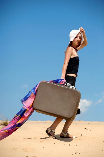 Vacker flicka går på en sand med en suitc — Stockfoto
