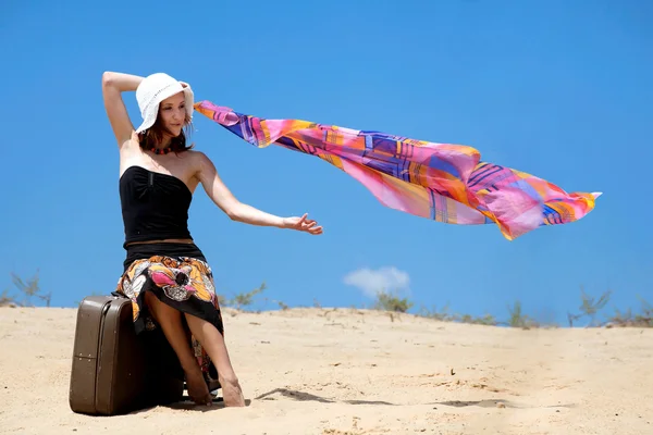 Чемодан стоит на песчаном пляже и девушка — стоковое фото