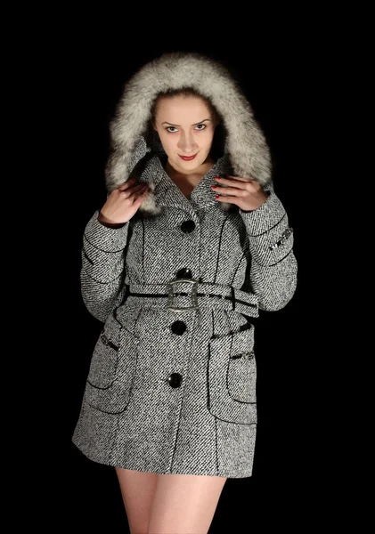 Frau im grauen Mantel auf schwarzem Hintergrund — Stockfoto