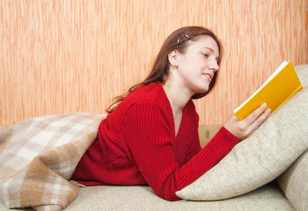 Hübsches junges Mädchen liest Buch auf dem Sofa — Stockfoto