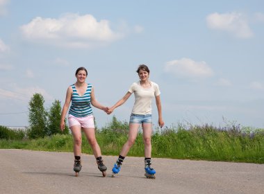 Two Young girls on roller blades clipart