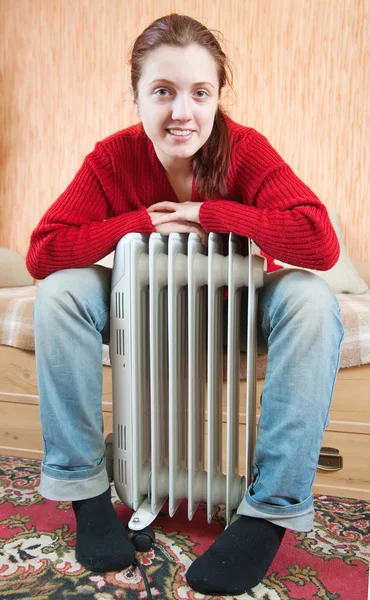 Girl is sitting by a oil heater — Stock Photo, Image