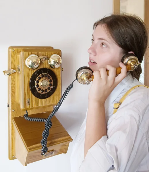Girl is speaking by retro wooden phone — Stock Photo, Image