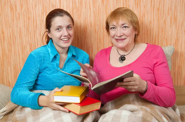 Two happy women reading a book on sofa — Stock Photo, Image