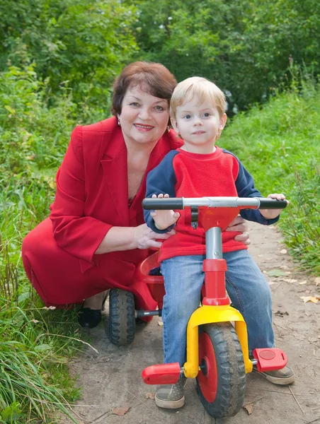 Üç tekerlekli bisiklet çocuk ile büyükanne — Stok fotoğraf