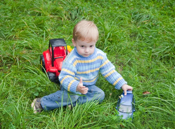 Мальчик играет в игрушечный грузовик в траве — стоковое фото