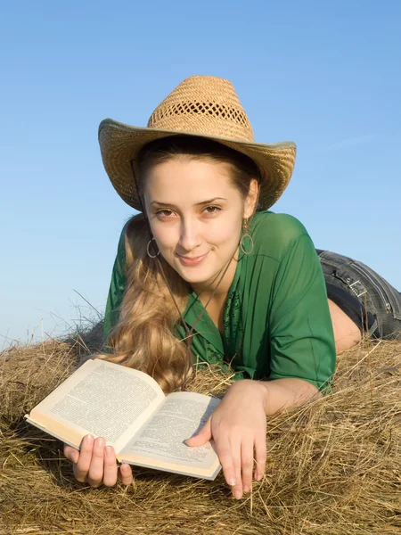 Flickan läsa på färskt hö — Stockfoto