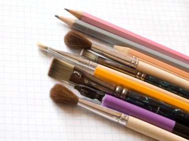 Pencils and brushes on copy-book clipart