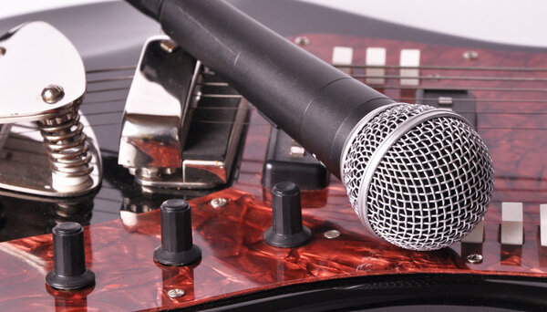 Picture of microphone lying on a guitar on a white background