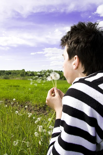 Teenager blowing dandelion — Stock Photo, Image