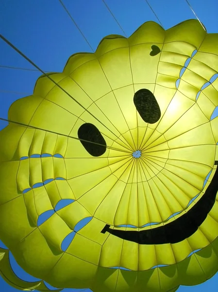 Yellow fun parachute with smiling person — Stock Photo, Image