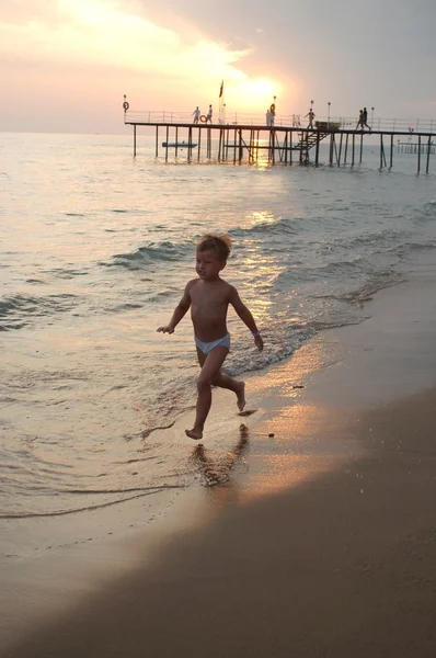 Счастливый мальчик бежит по пляжу в — стоковое фото