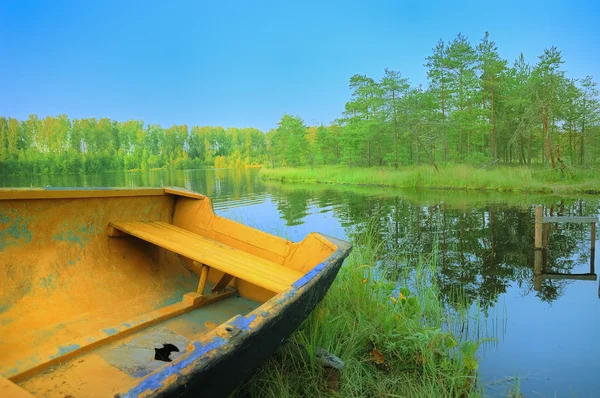 Човен з діркою на озері під блакитним небом — стокове фото