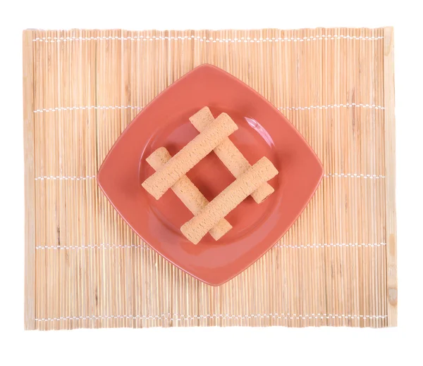 Galleta y un plato en una servilleta de bambú —  Fotos de Stock