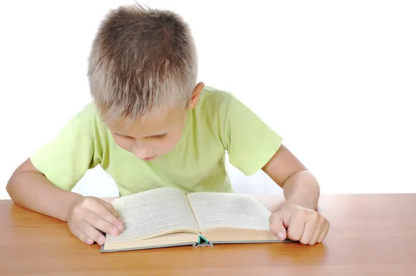 Rapaz com o livro atrás de uma mesa — Fotografia de Stock