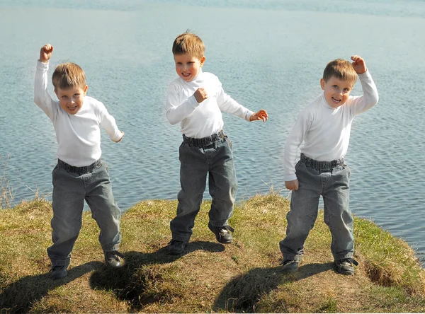 Three boys dance on green grass — Stock Photo, Image