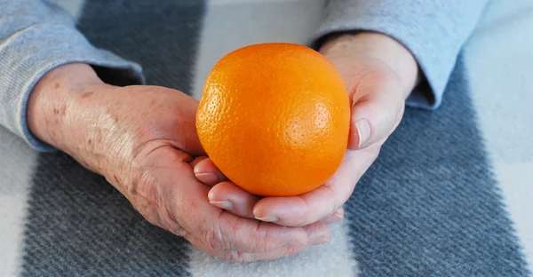 Mains de la femme âgée à l'orange — Photo