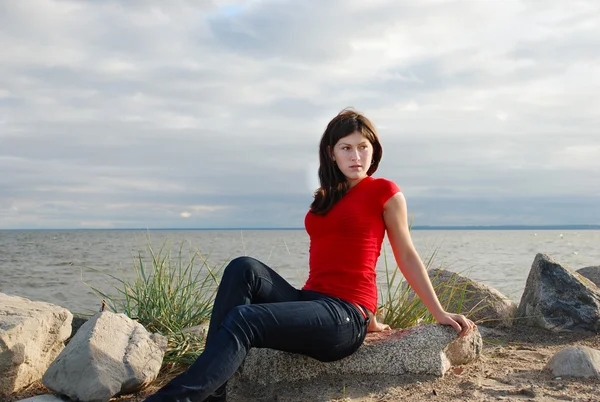 La chica se sienta en la costa — Foto de Stock