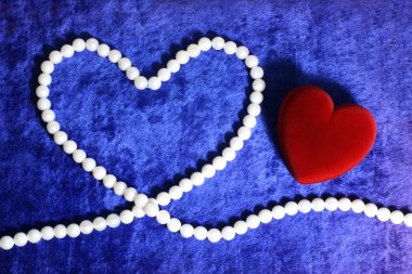 Red heart and pearly neacklace on blue v clipart