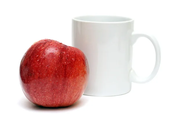 Красное яблоко и белая кружка — стоковое фото