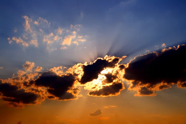 Raios solares atrás de nuvens escuras no céu — Fotografia de Stock