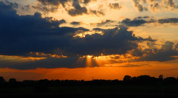 Sun behind dark clouds in sky — Stock Photo, Image