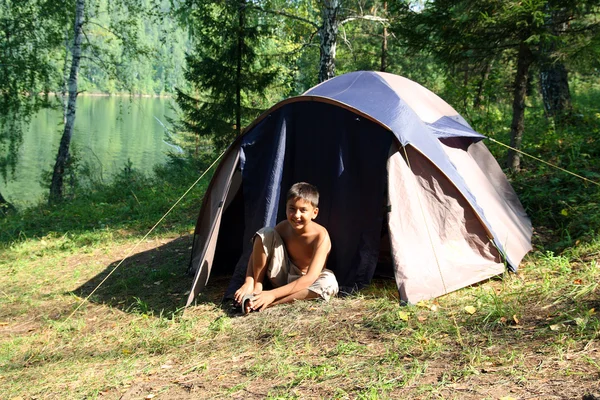 Улыбающийся мальчик возле палатки — стоковое фото