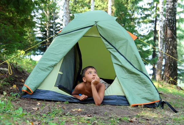 Задумчивый мальчик в палатке — стоковое фото