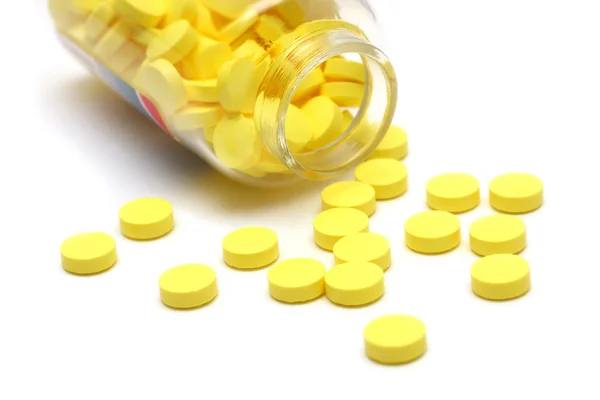 Žluté tablety kolem průhlednou láhev — Stock fotografie