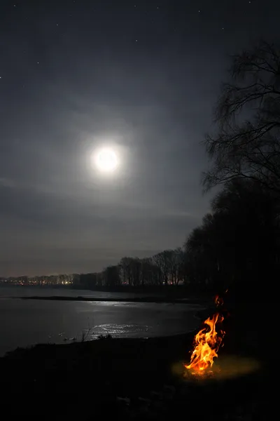Bonfire flame and moon over lake — Stock Photo, Image