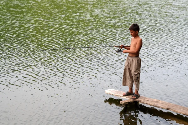 Boy fishing with spinning on stage — Stock Photo, Image
