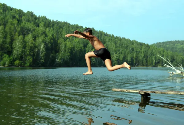 Boy jumping in lake — Zdjęcie stockowe