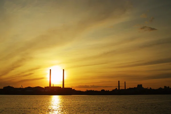 Solen inställningar bakom kraftverket rör — Stockfoto