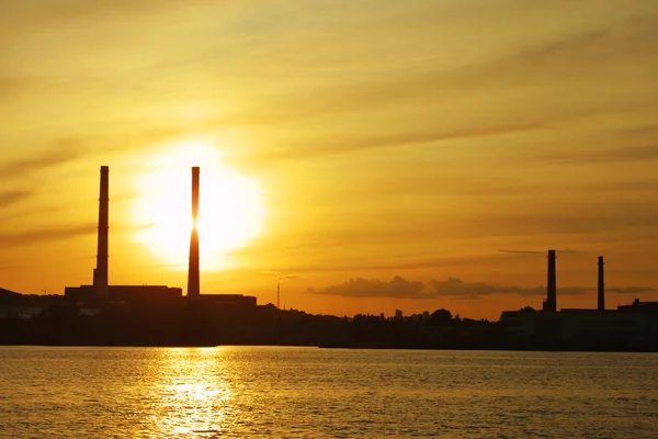 Solen inställningar bakom kraftverket rör — Stockfoto