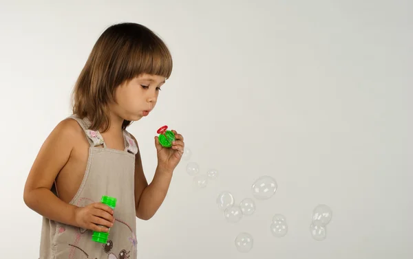 Cute little girl blowing soap bubbles — Stock Photo, Image